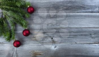 Merry Christmas background with real fir branches and red ball ornaments on natural rustic wooden boards