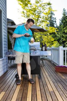 Mature man pouring himself a beer before the BBQ party on the outdoor home deck 