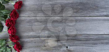 Red roses over weathered wooden planks for love holiday concept background