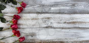 Circle of real red flowers on left side of rustic wooden planks for mothers day or valentines holiday 