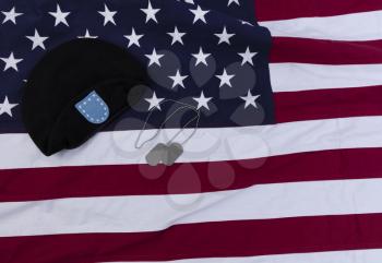 Waving American flag with military beret cap and ID tags for happy memorial or Independence Day background concept 