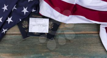 American flag with covid 19 Vaccination record card and US Passports on fade blue rustic wooden planks for travel requirement concept 