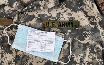 Covid 19 vaccination record card and personal facemask on US Army military uniform.  Individual record for use during the covid 19 coronavirus global pandemic 