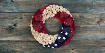 Wreath with United States national colors of red, white and blue with stars on faded blue wooden planks for happy memorial or Independence Day background concept 