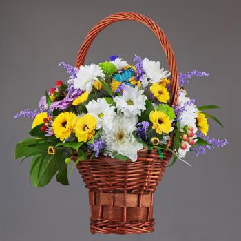 Colorful flower bouquet arrangement centerpiece in wicker basket on grey background. Closeup.