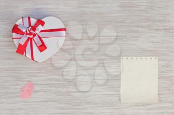 Valentine`s Day gift, heart and paper on wooden background. Closeup.