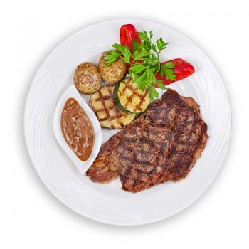 Grilled steak, baked potatoes and vegetables on white plate isolated on white background.
