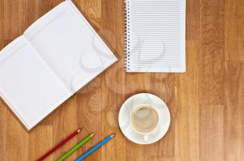 Blank notepad with office supplies and cup of coffee on wooden table. Above view.