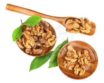 Handful of walnuts in wooden bowls, scoop and green leaves isolated on white background. Closeup.