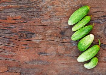 Juicy ripe green cucumbers on old wooden background. Closeup.