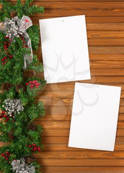 Garland with Christmas ornaments, pine cones and sheets of paper on wooden background.