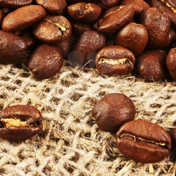 Roasted coffee beans on burlap background. Macro shot with tilt effect.