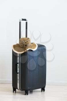 Large family polycarbonate luggage and summer sunny wicker hat on white wooden background. 
