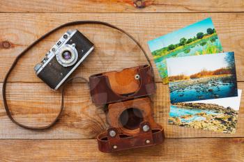 Vintage, very old film camera and old foto on brown wooden background.