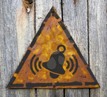 Royalty Free Photo of a Ringing Bell on a Rusty Sign Against a Wooden Wall