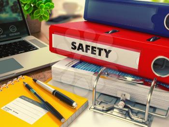 Red Office Folder with Inscription Safety on Office Desktop with Office Supplies and Modern Laptop. Business Concept on Blurred Background. Toned Image.