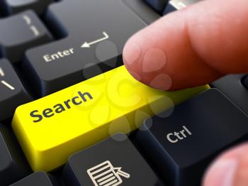 Search - Written on Yellow Keyboard Key. Male Hand Presses Button on Black PC Keyboard. Closeup View. Blurred Background.