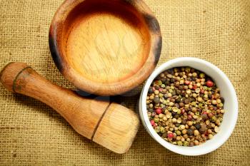 Macro shot of peppercorns and a wooden grinder and grinding bowl