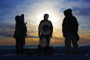 Silhouettes of the three backcountry freeriders in evening (Dragobrat ski resort, Ukraine).