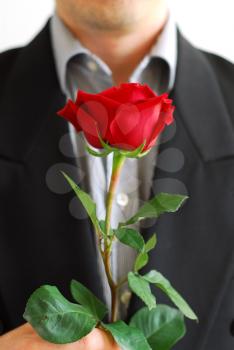 Man in black suit holding a red rose