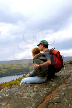 A parent and a child sitting on a cliff edge enjoying scenic view