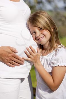 Family affairs - Girl is touching round belly of her pregnant mother in eager anticipation of the new child