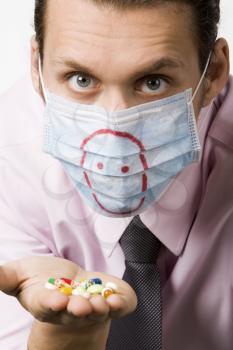 Photo of masked man holding pills and looking at camera