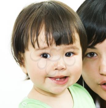 Close-up of small girls face looking at camera with her mother on the background