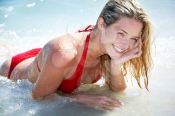 Portrait of pretty girl in red swimsuit lying in the sea    