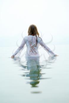 Rear view of beautiful female bathing in blue water