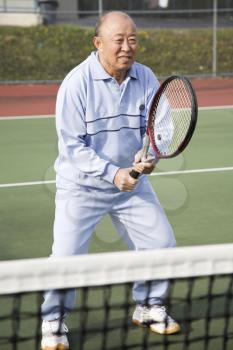 A shot of a senior asian man playing tennis
