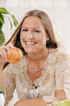 Beautiful girl holding apple in hand, smiling.