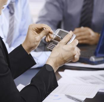 Smartphone handheld in closeup, colleagues working in background.