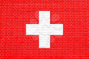 Flag of Switzerland on brick wall texture background. Swiss national flag.