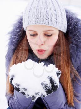 Young girl blowing on snow in their hands