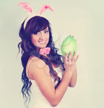 Beautiful woman dressed as a rabbit holding an egg,tinted