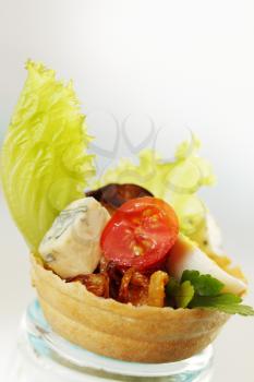 Cold appetizer in a waffle basket with cheese and tomato