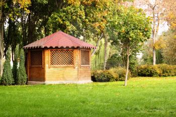 wooden gazebo on the green lawn with tree