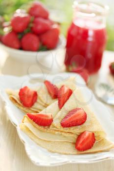 Fried pancakes with fresh strawberries and jam