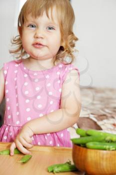 The girl in a polka dot dress eating peas