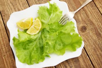 Fresh leaves of lettuce with lemon on a plate