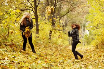 two friends throw each other autumn leaves