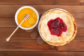 Pancakes with jam and honey on a wooden table. Top view .
