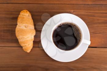 Cup of coffee on the table croissant. Top view .