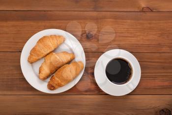 Coffee and croissants on a wooden table. View from above .