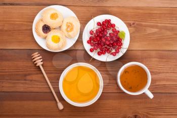 Cup of tea honey biscuits and currants on a wooden table. View from above .