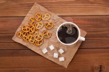 Cup of coffee and tasty pretzel on a wooden background. Top view.