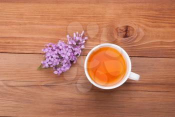 Cup of tea and lilac flowers on a wooden background.