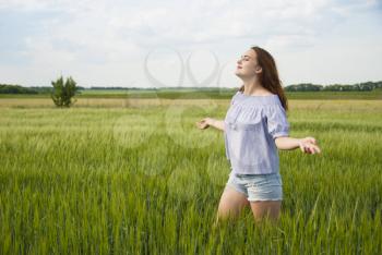 Happy beautiful girl in a field enjoying nature.