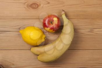 Lemon apple and bananas on a wooden background. View from above .